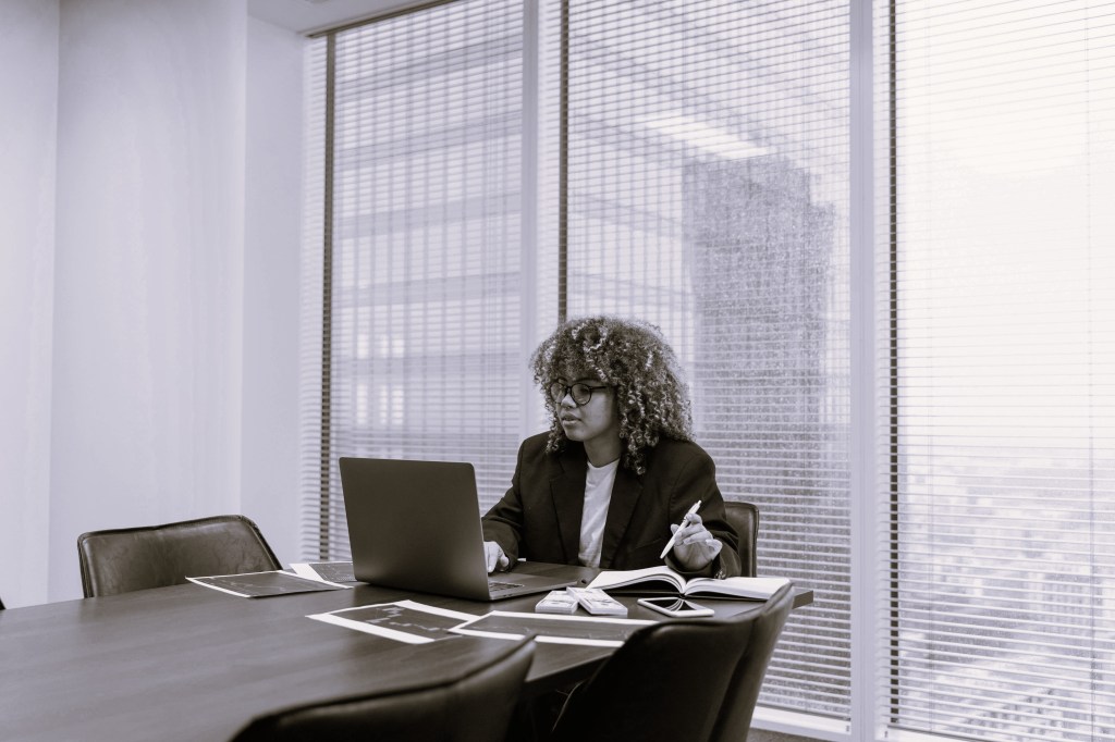 A black-and-white photo of a woman at a desk launching a startup